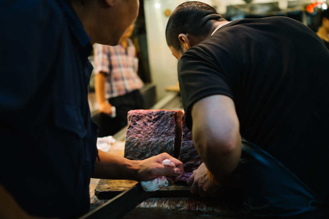 Cutting a tuna portion. It started as a two-man job, but soon another joined in.