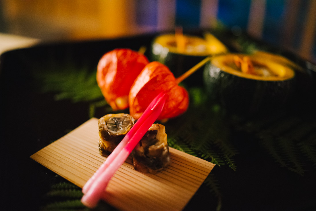 From front to back: eel sushi roll with ginger root, fried corn cake, sushi rolls and a sweet river shrimp inside a quash.