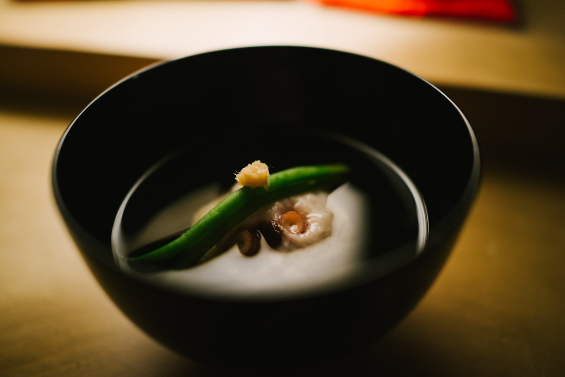 Clear soup with octopus dumpling and green bean, topped with ginger.